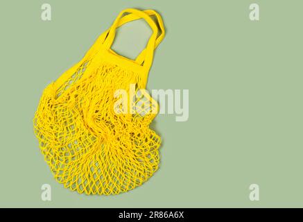 Yellow mesh string bag on green. International plastic free day background. 3rd of July. Copy space. Top view Stock Photo