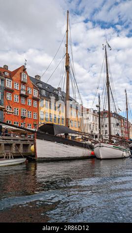 Copenhagen, Denmark - September 12, 2010: Portrait. Wooden boats on water docked in front of iconic Nyhavn restaurant facades in bright colors under b Stock Photo