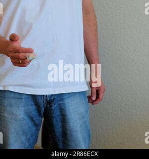 Man offering Tesla ecstasy pills in a plastic baggie; shaped like a shield with the Tesla logo; 240 milligrams of recreational MDMA Molly, drugs. Stock Photo