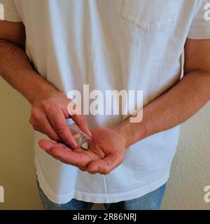 Man with Tesla ecstasy pills baggie; pills shaped like a shield with the Tesla logo; 240 milligrams of recreational MDMA, Molly, drugs. Stock Photo