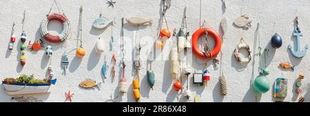 Nautical themed fishing gear, artifacts and decoration from the sea on a white wash pebbledash wall in the coastal seaside fishing village of Lower La Stock Photo