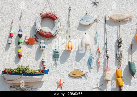 Nautical themed fishing gear, artifacts and decoration from the sea on a white wash pebbledash wall in the coastal seaside fishing village of Lower La Stock Photo