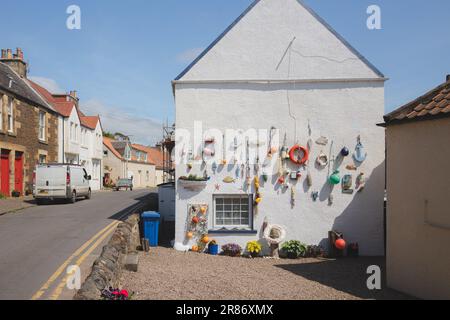 Lower Largo, UK - June 9 2023: Nautical themed fishing gear, artifacts and decoration from the sea on a white wash pebbledash wall in the coastal seas Stock Photo