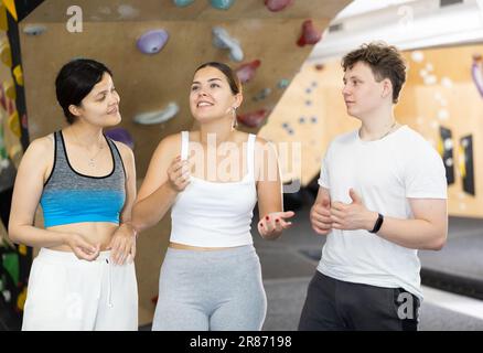 Asian girl, European woman and teenage guy - group of friends stand actively relaxing in climb hall Stock Photo