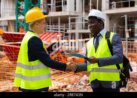 Two engineers concluding agreement and shaking hands Stock Photo