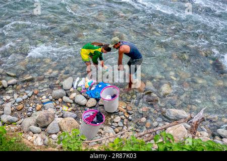 Occidental Mindoro Province, Philippines - June 10, 2023. A Filipino man and woman washing laundry by hand in a river on Mindoro Island. Stock Photo