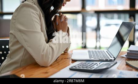 Close-up rear view image of a professional Asian businesswoman focuses on her tasks on her laptop, analyzing business financial data, and working at h Stock Photo