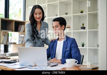 A professional millennial Asian female boss is training and briefing a male worker in the office on a new project. Stock Photo