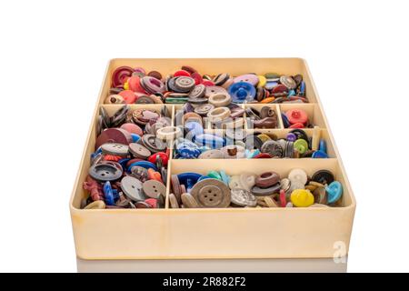 Many buttons in plastic container, macro isolated on white background. Stock Photo