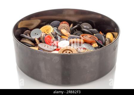 Many buttons in a black round, plastic container, macro, isolated on white background. Stock Photo