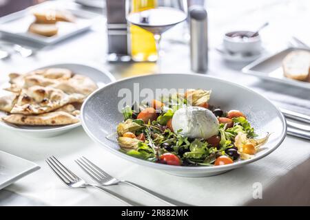 Buffalo salad served in a restaurant with wine and pixzza bread. Stock Photo
