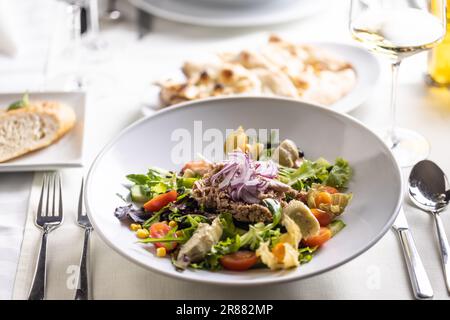 Mixed greens, corn, cherry tomatoes, avocado salad with tuna fish and raw onion on top. Stock Photo