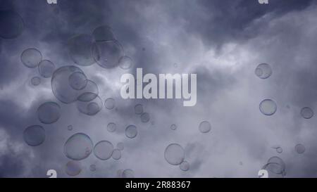 Soap bubbles are flying on gray cloudy sky background Stock Photo