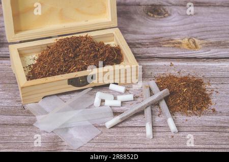 box of rolling tobacco Wooden box with rolling tobacco, rolled cigarettes, cigarette papers and  filters Stock Photo