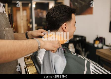 Back view of man sitting on chair in barbershop.  Stock Photo