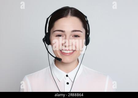 Hotline operator with modern headset on light grey background. Customer support Stock Photo