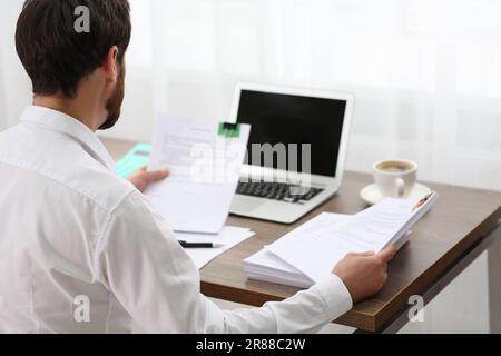 Businessman working with documents at table in office, back view Stock Photo