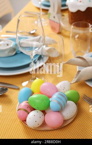 Festive table setting with painted eggs, glasses and cutlery. Easter celebration Stock Photo
