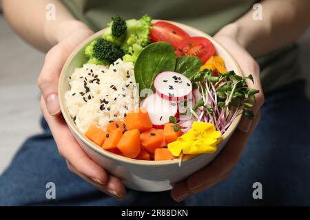 Woman holding bowl with different vegetables and rice, closeup. Vegan diet Stock Photo