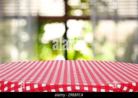 Red and white checkered tablecloth on table near window. Space for design Stock Photo