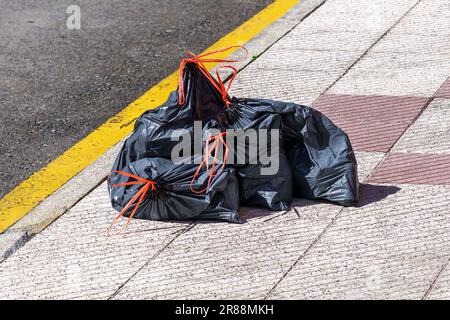 Discarded full plastic garbage bags on an empty city street close up. Environment pollution concept Stock Photo