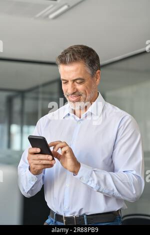 Mature business man office employee standing using cell phone. Stock Photo