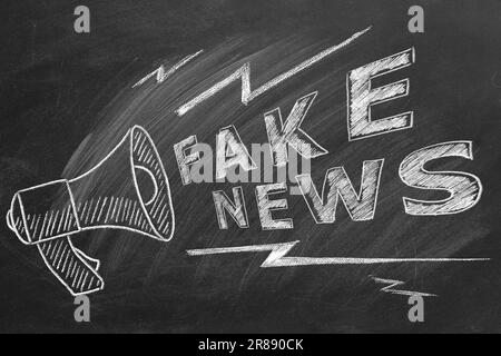 Megaphone with the text FAKE NEWS drawn in chalk on a blackboard. Hand drawn illustration. Information and disinformation concept. Stock Photo