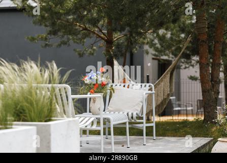 Wild flower bouquet (Cornflowers, chamomiles wheat and poppies) in terracotta vase on summer terrace. Wildflower and grass varieties. Stock Photo