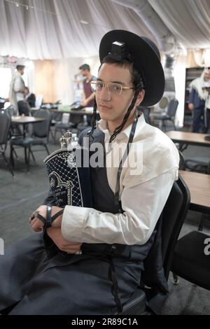 Posed photo of an orthodox Jewish boy holding a Torah scroll after it was read & before it was returned to the holy ark. In Monsey, NY, June 2023. Stock Photo