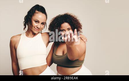 Two Plus Size Women In Sports Clothes Standing In Young Female Athletes  Posing Together Against Brown Background Stock Photo, Female Athletes In  Dresses