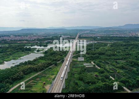 (230620) -- SHENGZHOU, June 20, 2023 (Xinhua) -- This aerial photo taken on June 19, 2023 shows a bullet train running on the Hangzhou-Shaoxing-Taizhou intercity railway in Shengzhou, east China's Zhejiang Province. The Hangzhou-Shaoxing-Taizhou intercity railway is among China's first group of high-speed railway projects funded by a public-private partnership (PPP), with the private sector having a holding status. Since the railway's official operation in January 2022, more than 10 million passengers have travelled along it. The 266.9-kilometer rail line, with a designed speed of 350 kilomete Stock Photo