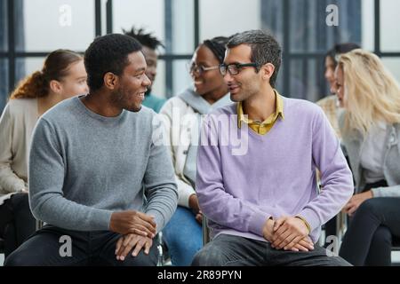 Happy multiethnic employees having fun while discussing project, sharing ideas, informal brainstorming sitting on chairs Stock Photo