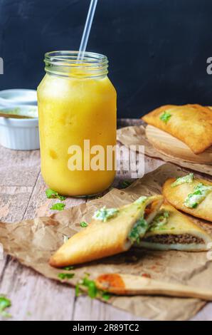 Passion fruit juice and empanada typical food from Venezuela, on wooden table and black background Stock Photo