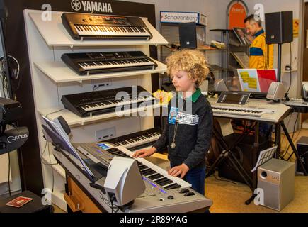Netherlands, boy is trying a keyboard in a music shop before he and his father are making a decision for a brand and type to buy. Stock Photo