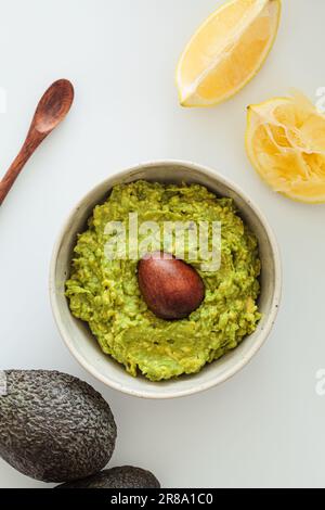 Guacamole with bone in a white bowl, white background, top view. Healthy plant-based food concept. Stock Photo
