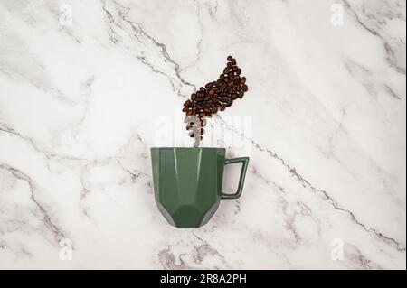 Top view of coffee cup on white marble background. Coffee beans and green cup flat lay. Copy space. Stock Photo