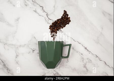 Top view of coffee cup on white marble background. Coffee beans and green cup flat lay. Copy space. Stock Photo