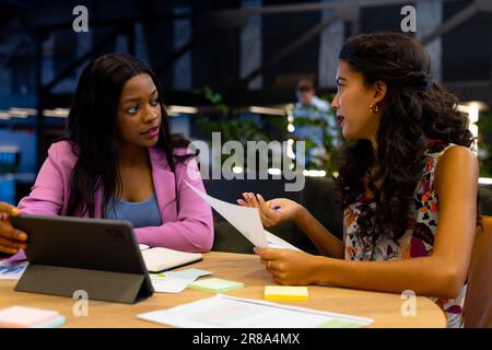 Diverse female colleagues in discussion using tablet in casual office meeting Stock Photo