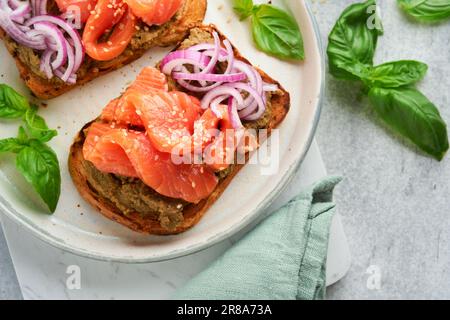 Sandwiches with salted salmon, avocado guacamole, red onions and basil. Smorrebrod. Set of danish open sandwiches. Healthy food, breakfast. Clean eati Stock Photo