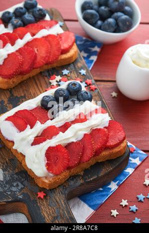 4th of July American Independence Day food. American flag sandwich with strawberries, blueberries, whipped sweet cream, soft cheese on toast bread. In Stock Photo