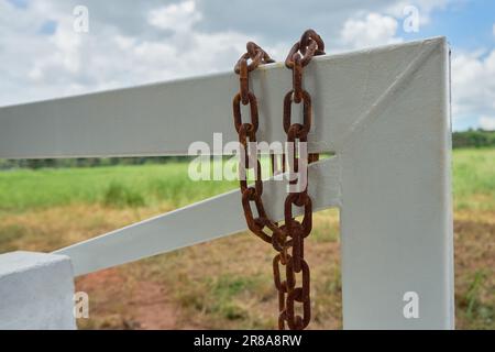 The rusty chain on a white gate Stock Photo