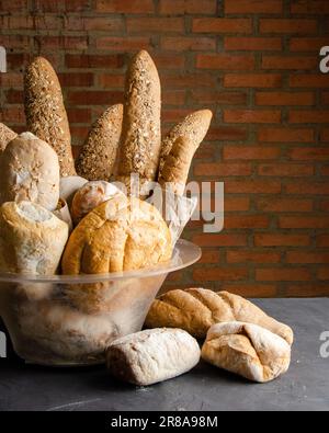 Basket with different types of breads. On black background, brick wall. Stock Photo