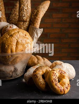Basket with different types of breads. On black background, brick wall. Stock Photo