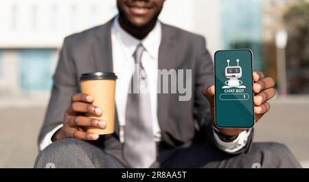 Cropped of black man in suit holding smartphone, using chatbot Stock Photo