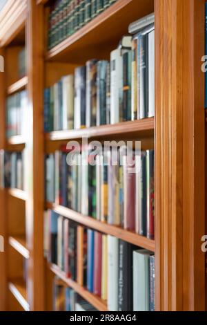Library full of books of different sizes and colors in the interior of a house. Stock Photo