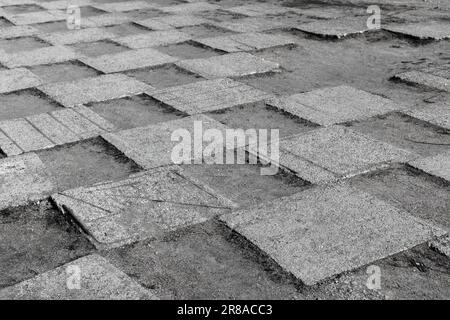 Grungy gray concrete tiles of an urban pavement lay on dusty ground in checker pattern, abstract architecture background photo Stock Photo