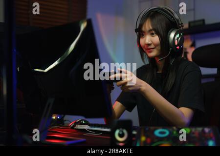 Female cyber hacker gamer using controller joystick to playing or streaming games on computer. Stock Photo