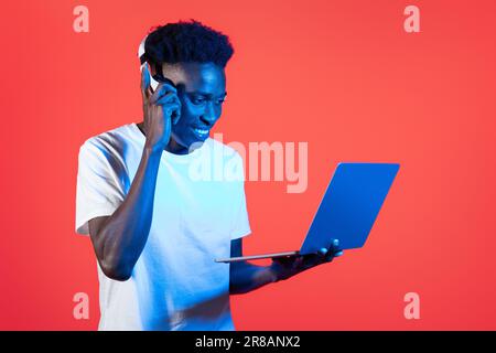 Cheerful young african man using headphones and computer Stock Photo