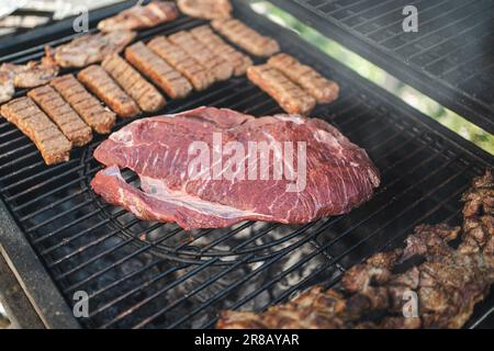A close-up of an assortment of grilled meats cooking on a hot plate Stock Photo
