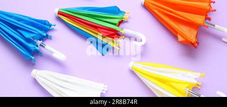 Many small umbrellas on lilac background Stock Photo